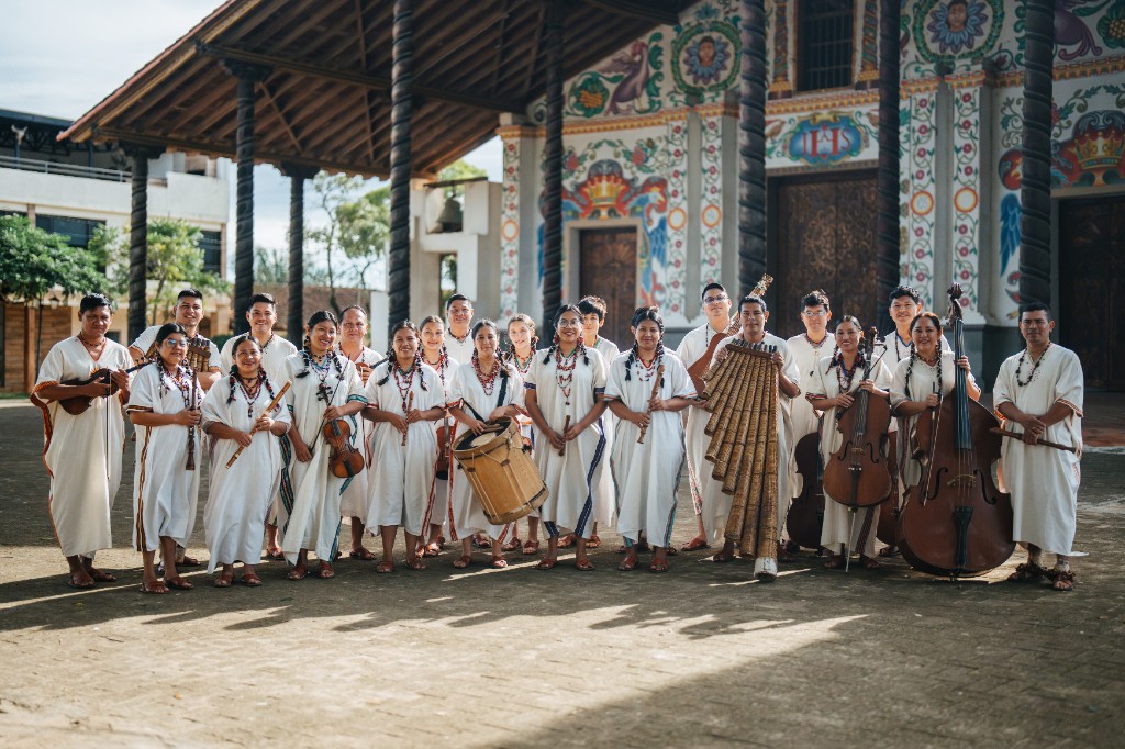 Ensamble Moxos in traditioneller Kleidung vor einer Missionskirche in San Ignacio de Moxos, mit Geigen, Flöten, Trommel und Panflöten